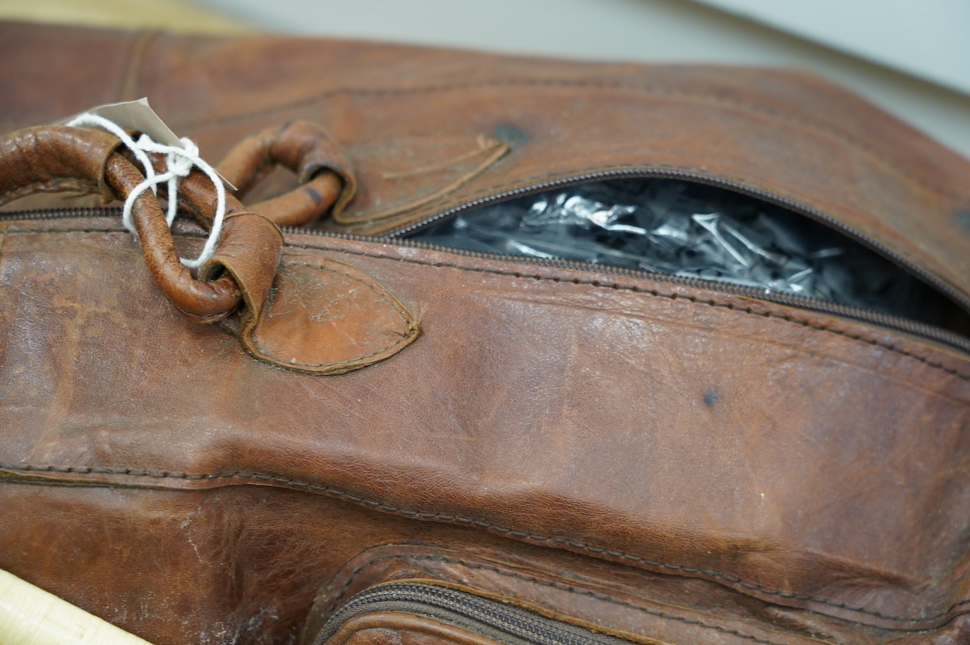 A leather sports holdall, with squash racket. Condition - poor to fair